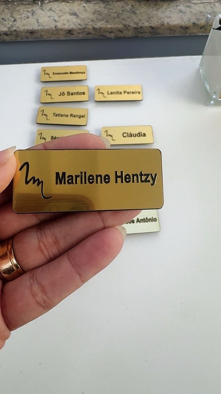 Broche dourado personalizado fotografado na mão da cliente